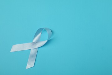 Light blue ribbon on color background, top view with space for text. Prostate cancer awareness