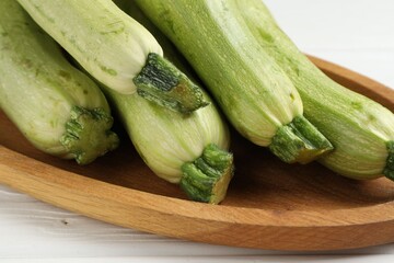 Raw green zucchinis on white wooden table, closeup