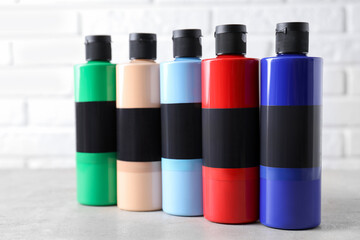 Acrylic paints of different colors in bottles on light table