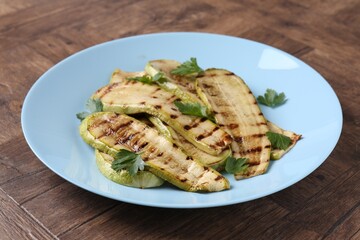 Tasty grilled courgette slices with parsley on wooden table