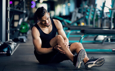 Plakat Sport Injury. Upset Arab Male Athlete Suffering From Knee Trauma While Training At Gym, Middle Eastern Man Sitting On Floor And Massaging Aching Area, Sporty Guy Frowning With Pain, Copy Space