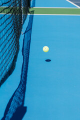 pickleball bouncing on a blue court on a sunny day