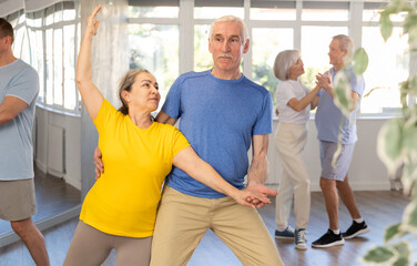 Couple of elderly man and elderly woman dancing waltz in studio