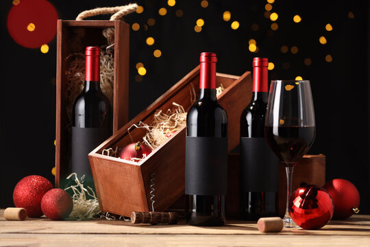 Bottles of wine, glass, wooden boxes, corks and red Christmas balls on table