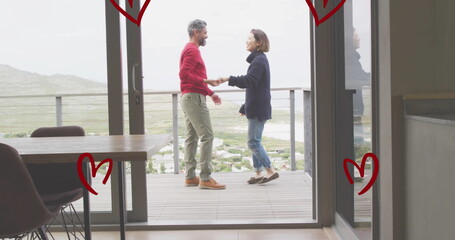 Image of hearts over diverse couple dancing on balcony