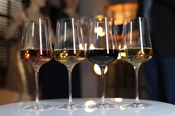 Different tasty wines in glasses on white table indoors, selective focus