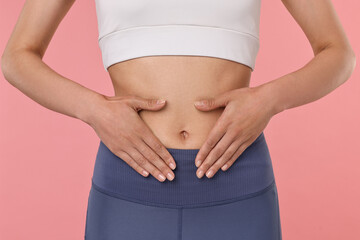 Healthy digestion. Woman touching her belly on pink background, closeup