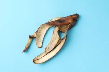 Banana peel with dark spots on light blue background, top view