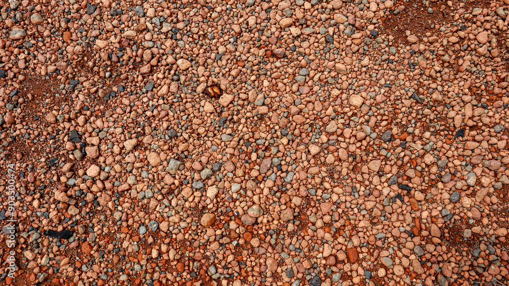 Poster a close-up view of a red gravel surface, showcasing the varied shapes and sizes of the pebbles creat