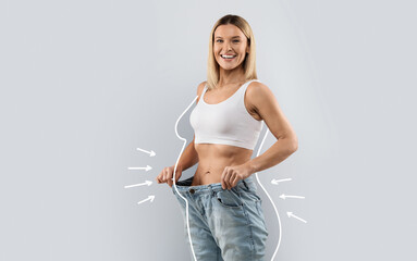 Cheery attractive slender middle aged blonde woman wearing huge jeans, showing results of diet,...