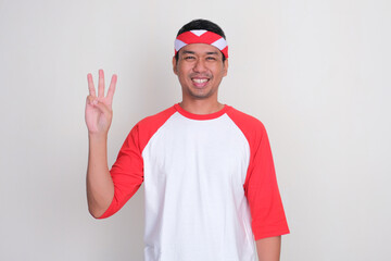 Naklejka premium Adult Asian man smiling at the camera while showing three fingers sign