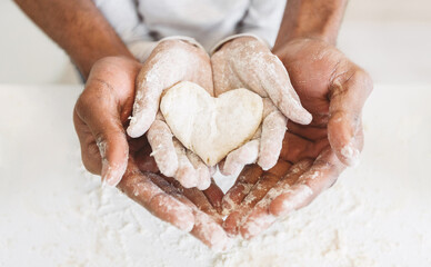 Afro man's hands holding childs hands with heart shaped pastry. Happy childhood concept