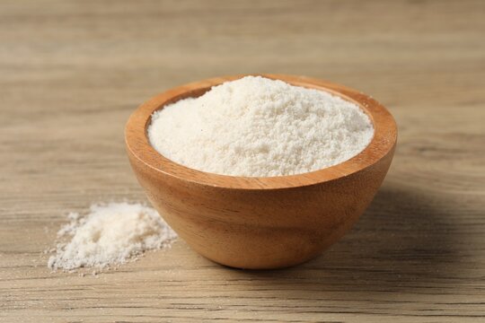 Fresh coconut flour in bowl on wooden table, closeup