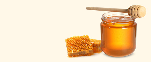 Organic honey in glass jar, wooden dipper and honeycomb on beige background. Banner design with space for text