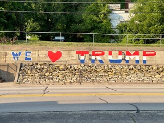 “We love Trump” painted in red, white and blue on a cement wall beside a highway. 