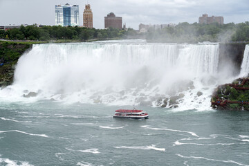 A tour boat cruises towards to mist at the base of the Horseshoe Falls in Niagara Falls Ontario.