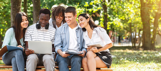Students Passtime. College Friends Sitting Outdoors With Laptop, Watching Videos Together, Having...