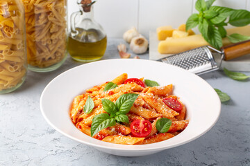 Classic italian pasta penne alla arrabiata with basil and freshly grated parmesan cheese on dark table. Penne pasta with chili sauce arrabbiata.