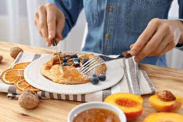 Fruit galette on plate and towel, man with cutlery at table on light background