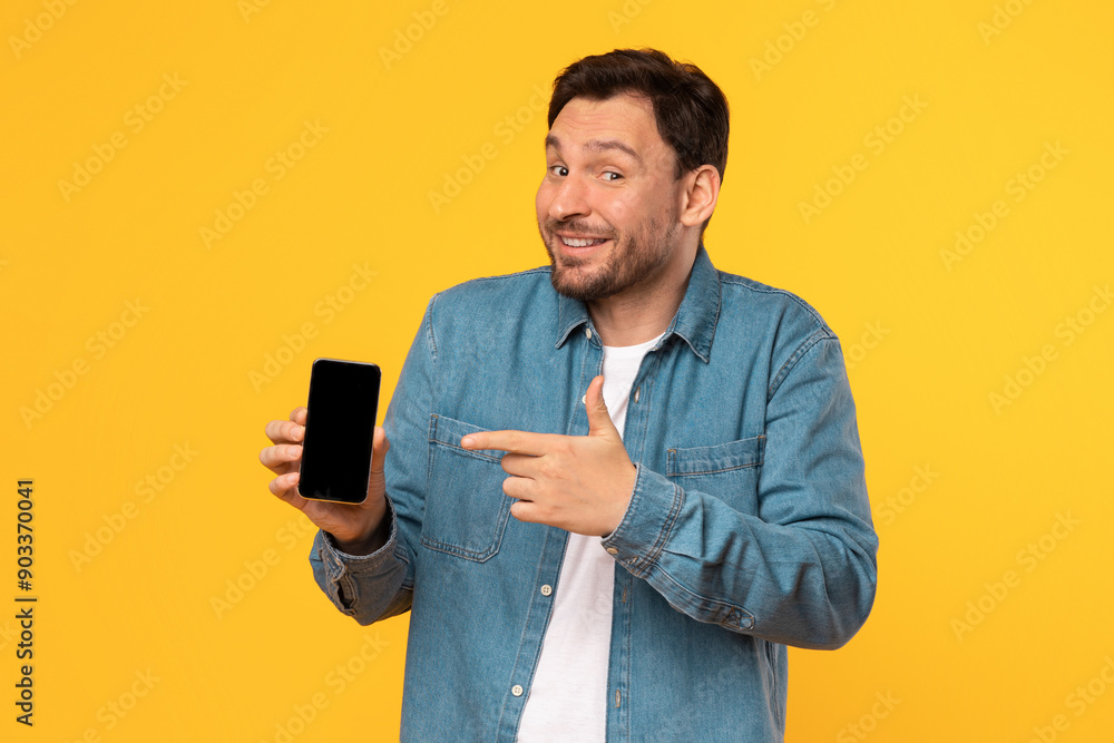 Poster a man in a blue denim shirt stands in front of a yellow background. he is holding a smartphone in hi