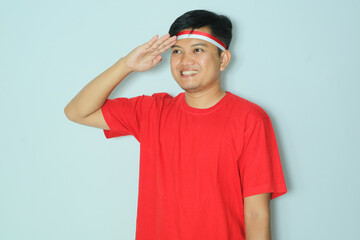 Indonesian man smiling proud while give salute pose. Wearing a red t-shirt