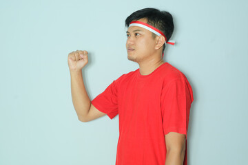 Indonesian man clenched fist showing a proud expression during independence day celebration. Wearing a red t-shirt