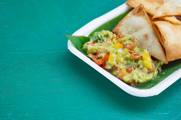 Fresh guacamole with crispy tortilla chips on eco-friendly plate.