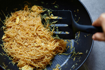 Close-up of stir-fry Rice Vermicelli with eggs in cooking pan 