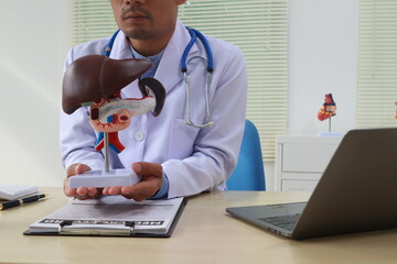 A male doctor sits at his desk in an office, liver health. He diagnoses and treats diseases like...