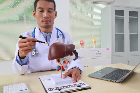 A male doctor sits at his desk in an office, liver health. He diagnoses and treats diseases like hepatitis, cirrhosis, and gallbladder disorders, using his expertise in gastroenterology