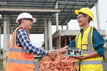 A male engineer, wearing a hardhat and helmet, examines blueprints on a construction site. Working...
