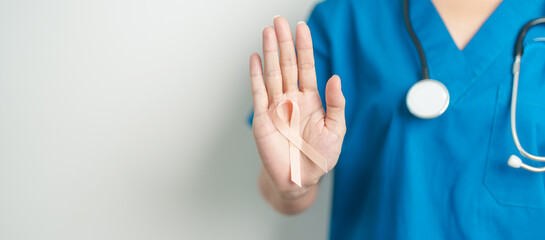 Doctor holding Peach Ribbon for September Uterine Cancer Awareness month. Uterus and Ovaries, Endometriosis, Hysterectomy, Uterine fibroids, Reproductive, Healthcare and World cancer day concept