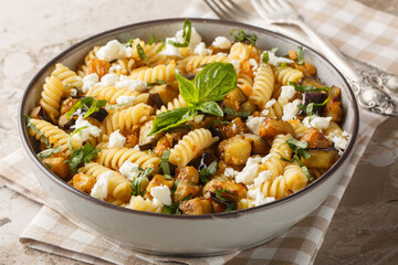 Traditional pasta dish of sauteed eggplant garlic and topped with feta closeup on the bowl on the table. Horizontal