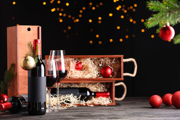 Bottles of wine, glasses, wooden boxes, fir twigs and Christmas balls on table
