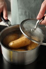 Woman boiling potatoes in saucepan on stove, closeup