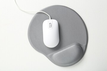 Computer mouse and mousepad with armrest on white table, top view