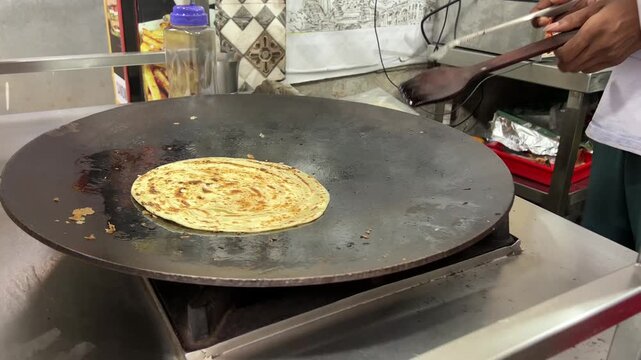 A man preparing lacha paratha at a shop in India