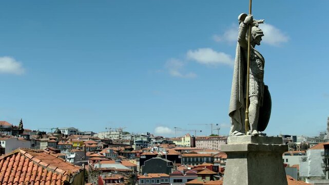 a Statue and the roofs of the houses in Porto, in the background.