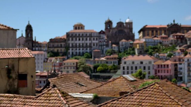 A view over the roof tops with some building and a church on a hill in the background, in Porto, Portugal.