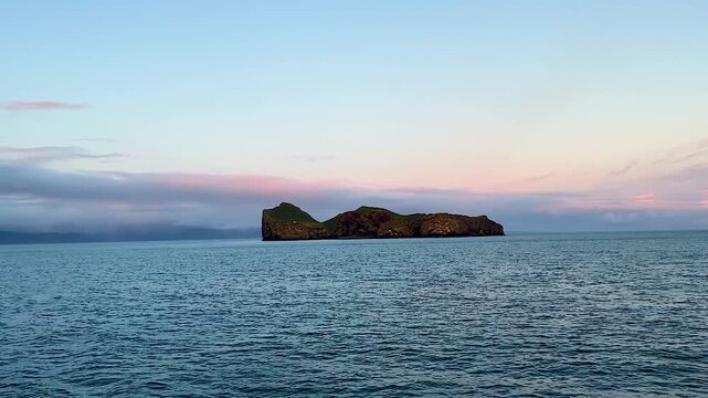 Wide view of distant secluded island Ellidaey with house and open ocean, Vestmannaeyjar, Iceland
