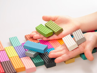 The child holds bright plastic clay in his hands, demonstrating the soft texture and rich colors