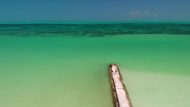 Drone view of an individual walking on rocks at Holbox Island's tropical beach.