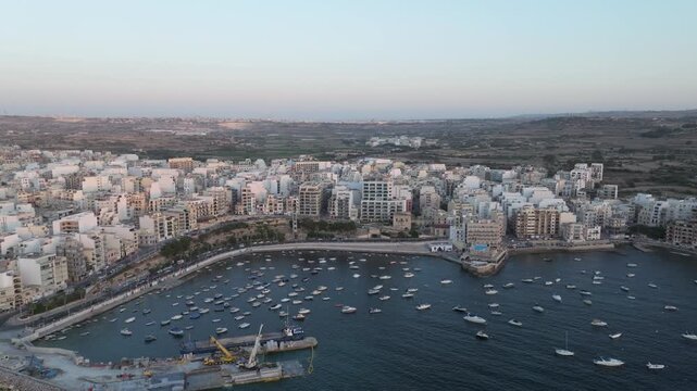 Boats At Bugibba Bay Marina In St. Paul's Bay Town With Seafront Buildings In Malta. - aerial shot