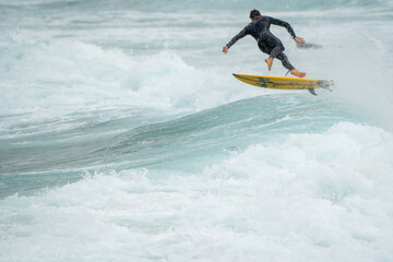 surfer on the wavesCaucasian male surfer Australian from behind in air after catching a wave,