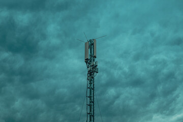 Obraz premium Mobile telephony signal repeater tower against overcast dramatic cloudy sky