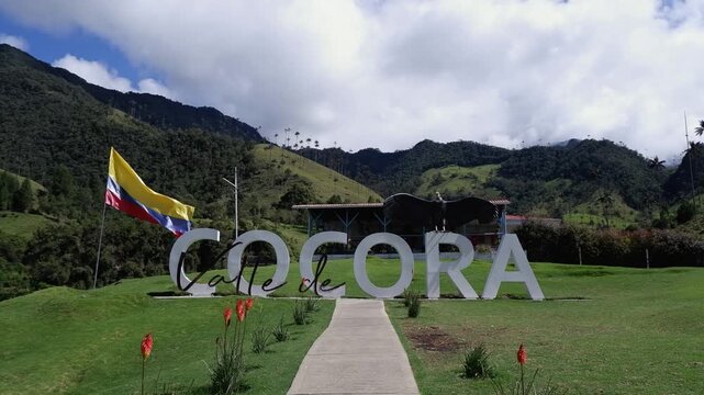 Flag of Colombia flutters over signage in scenic green Cocora Valley