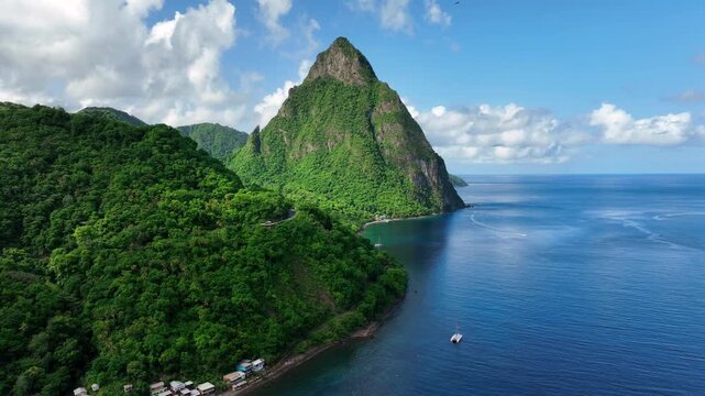 Coastal city of Soufriere with tropical coastline and turquoise ocean water. Large Mountain in Background. Aerial flight along coast. Saint Lucia,America. Wide shot.