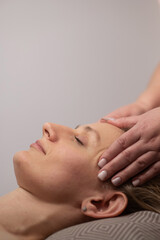 Caucasian woman undergoing a head and face massage procedure. Vertical photo.