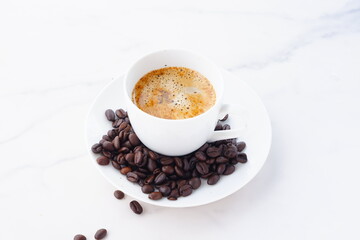 エスプレッソに牛乳をたっぷり入れたコーヒー、カフェ・ラッテと、深煎りしたコーヒー豆
