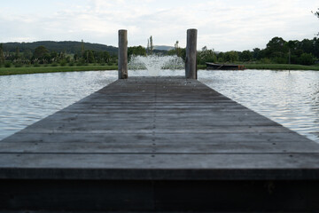 Fototapeta premium Rustic wooden pier dock on lake water fountain 